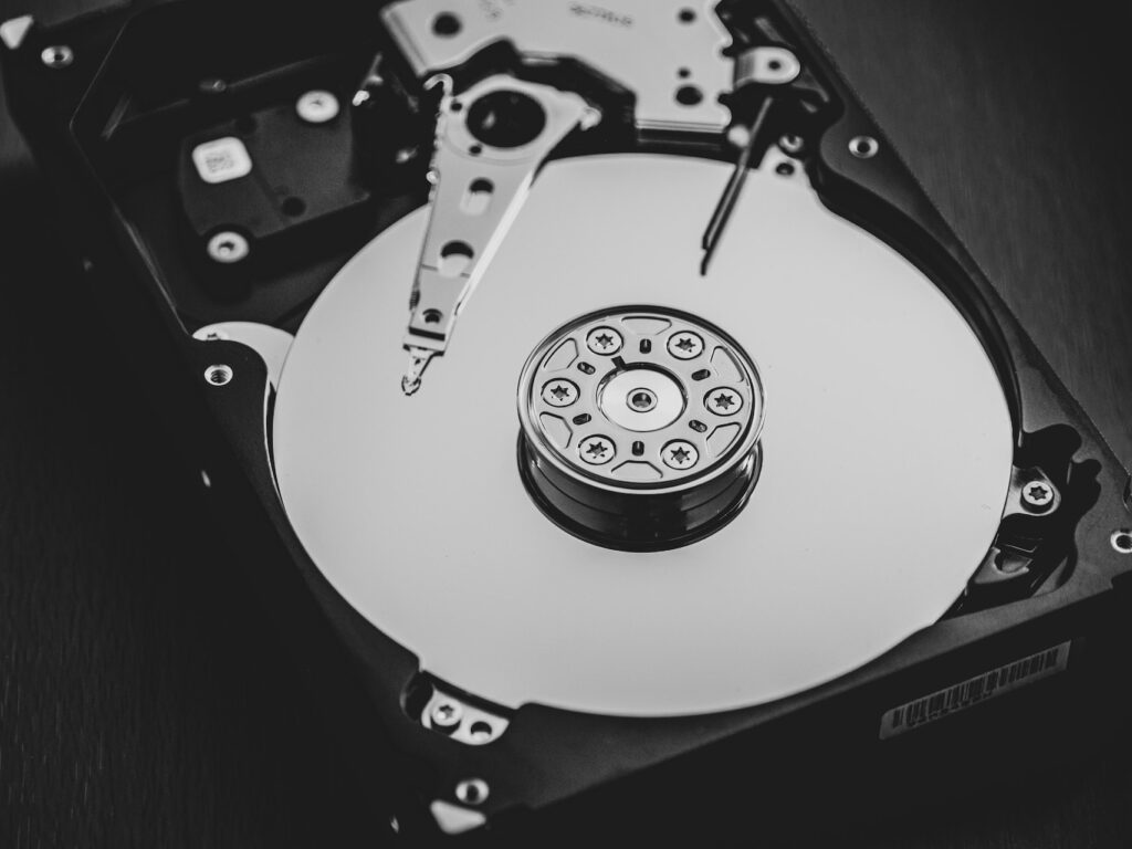 Black and white photo revealing the inner workings of a hard drive, with a spinning disk at its core.